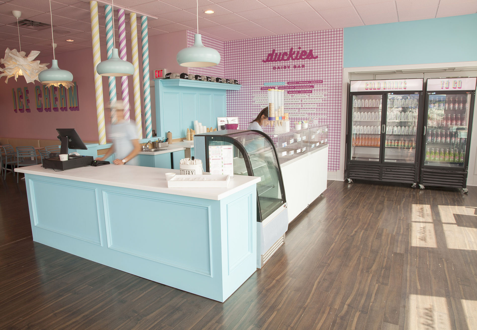 Interior of Duckies Dairy Bar with counter and cash register, and refrigerator with cold drinks.
