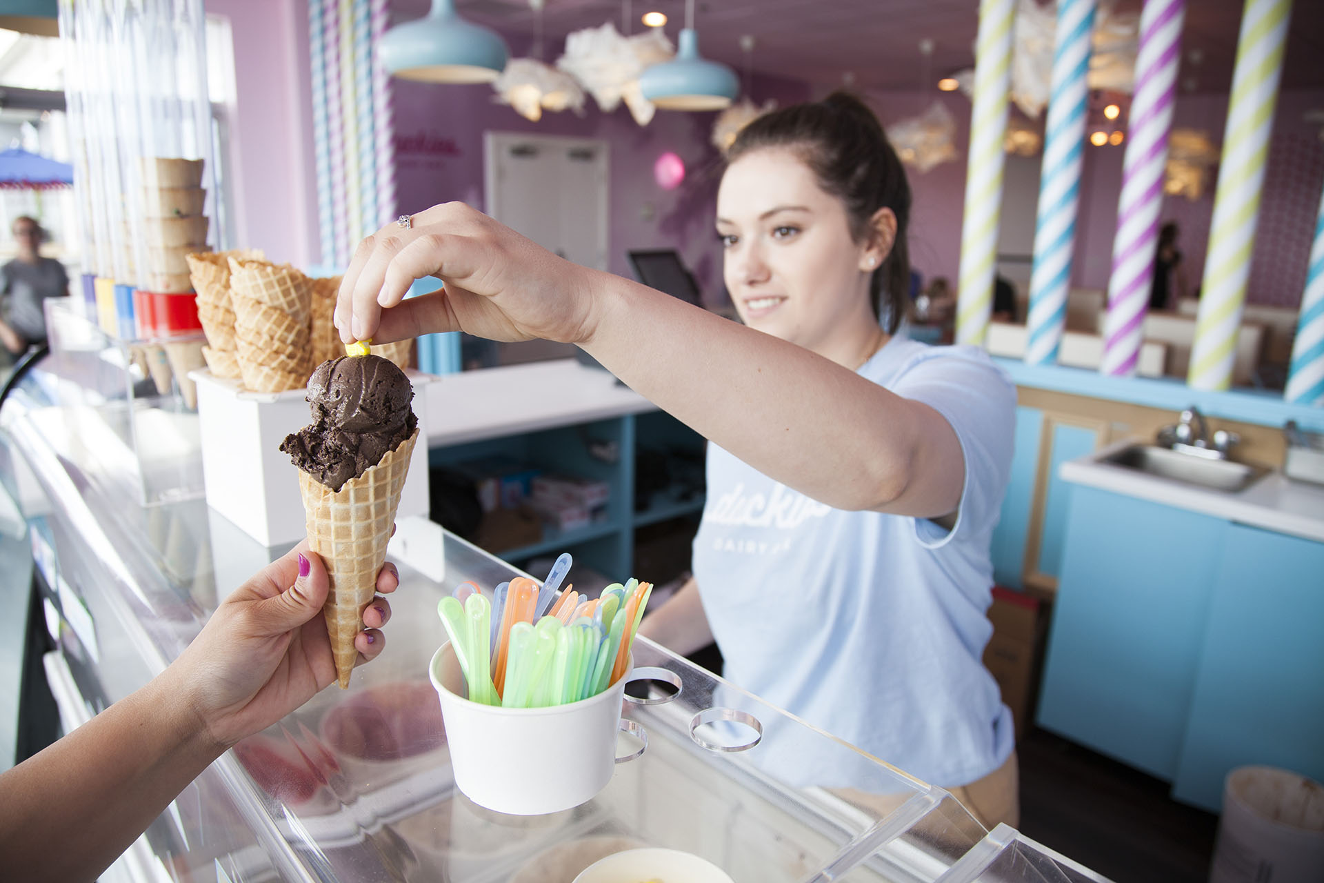 Staff member at Duckies Dairy Bar adding a confection to the top of an ice cream cone